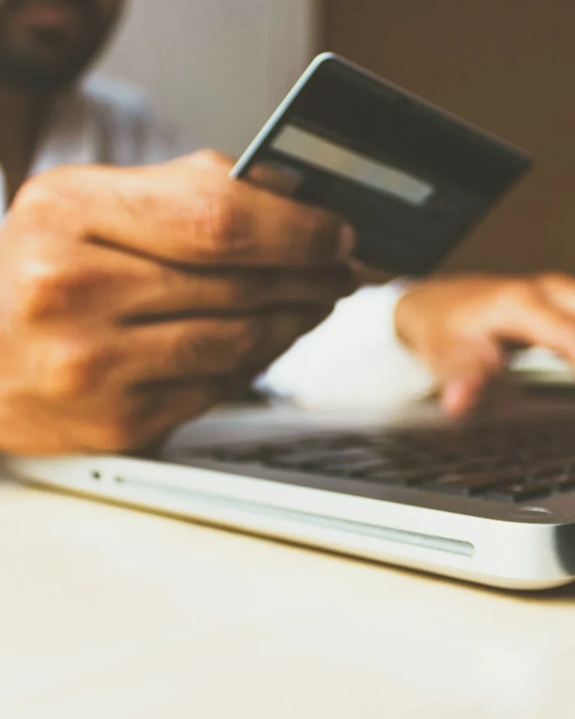 Shopper holding a payment card while buying on a laptop