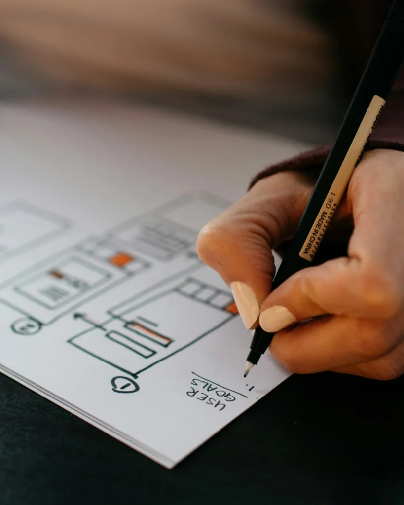 Designer sketching a landing page layout with a pen