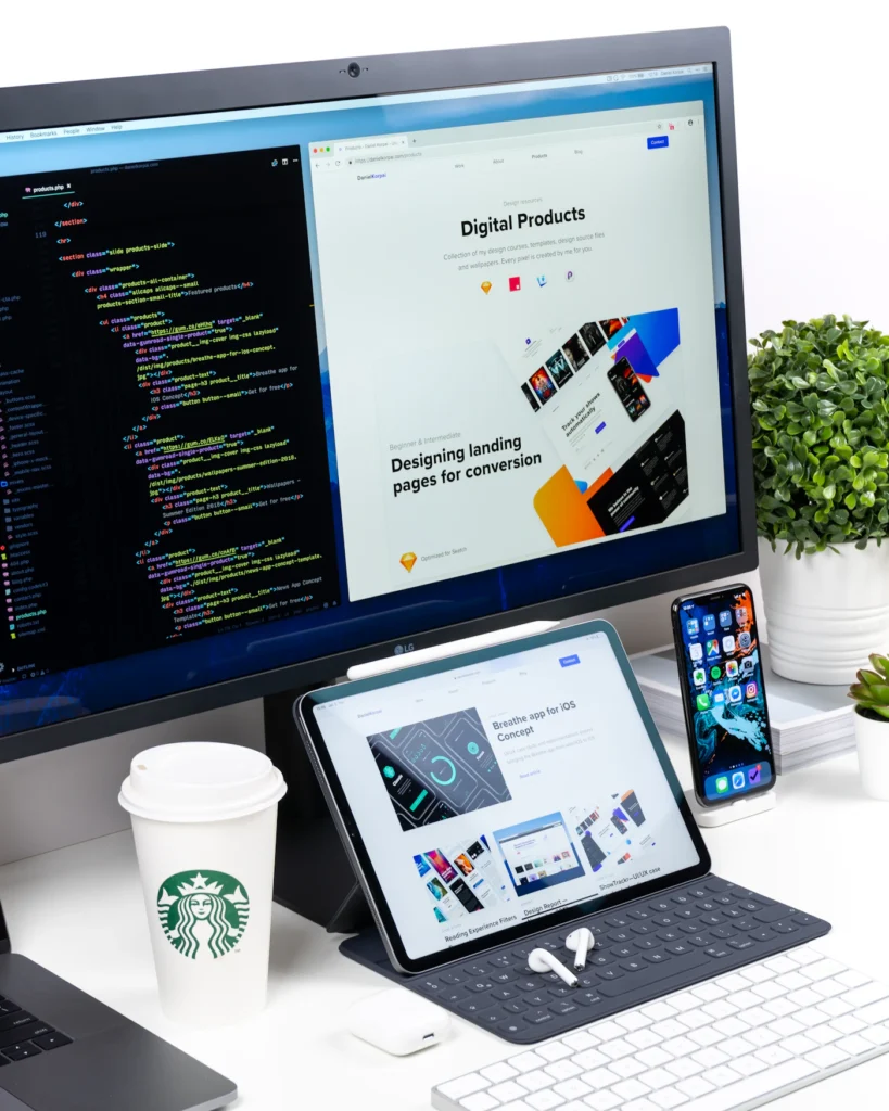 Monitor showing a landing page design next to code and a tablet