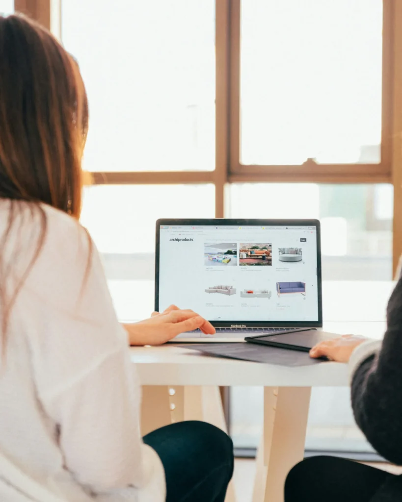 Two marketers reviewing ad results on a laptop